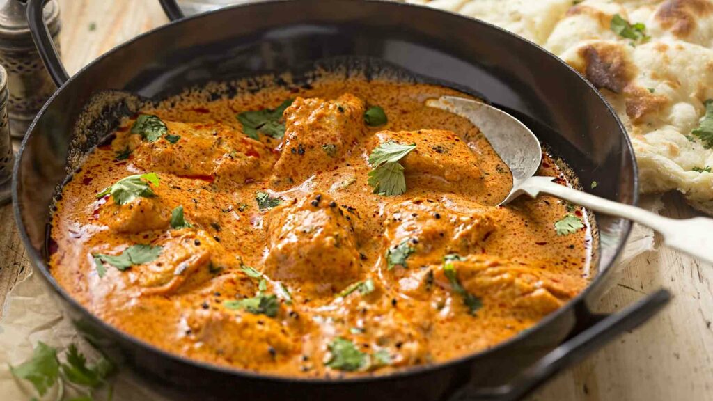 Butter Chicken in a kaadi placed in a wooden table near non