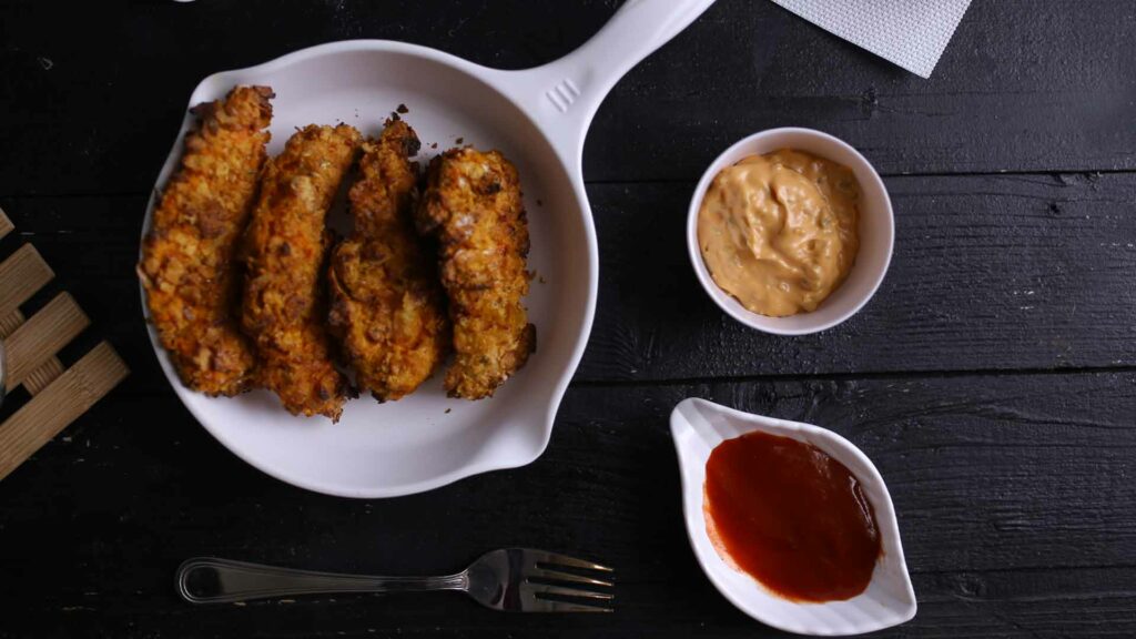 Chicken strips in white pan place in black background