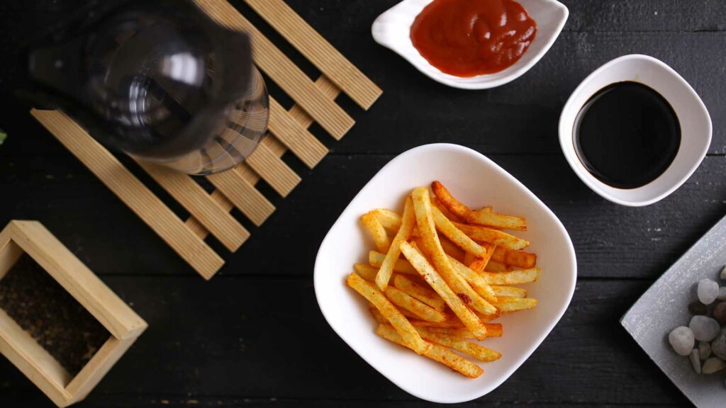 French Fries in a white bowl with tomato sauce with grey background